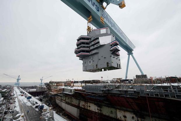 The 555-metric ton island is lowered onto the nuclear-powered aircraft carrier Gerald R. Ford.