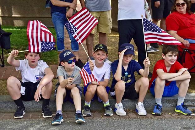 Children in attendance at the 2019 National Memorial Day Parade wave flags.