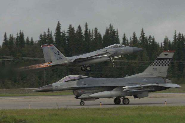 An F-15 takes off while an F-16 taxis on the flightline during RED FLAG-Alaska.