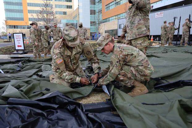 Members of the Maryland Army National set up a medium tent outside Adventist HealthCare White Oak Medical Center.