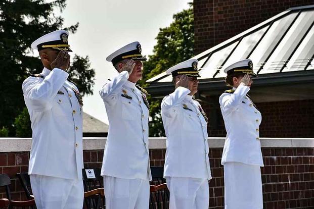 Rear Adm. Michelle Skubic, Capt. Jonathan Haynes, Capt. Doug Noble, and Captain Nick Rapley salute the National Ensign during the change of command ceremony.