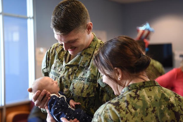 dual military couple looking at new baby