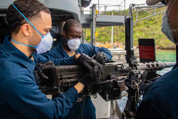 Sailors aboard the aircraft carrier USS Theodore Roosevelt inspect an M2HB machine gun. 