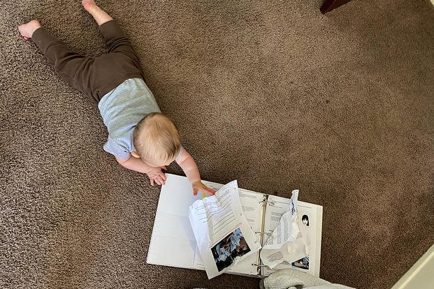 baby reading binder on the floor