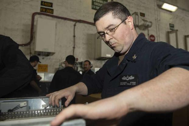 Machinist's Mate 2nd Class Nathaniel Atkins, assigned to the aircraft carrier Gerald R. Ford's engineering department, works on a large ice maker.