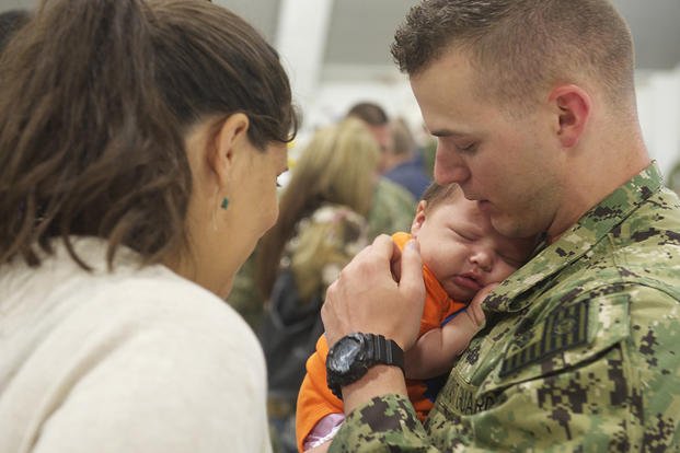 service member in uniform holding a newborn