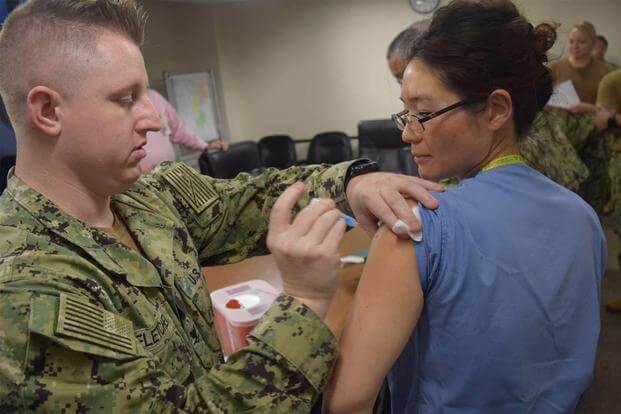Cmdr. Sanghee Park is on the receiving end of her annual influenza vaccination.