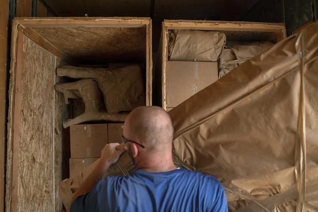 Movers pack a military members property into boxes.