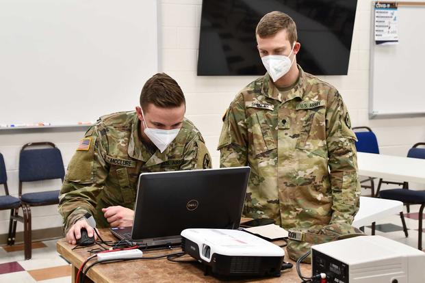 Two soldiers use a computer.