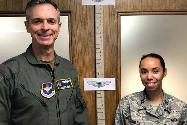Two airmen illustrate the varying standing heights of Air Force pilots.