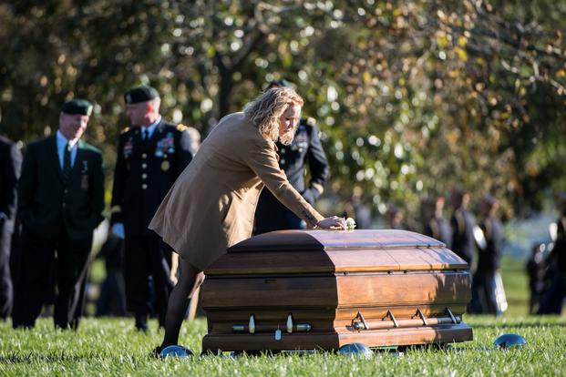 Michelle Black places a rose on her husband's casket  in Section 60 of Arlington National Cemetery.