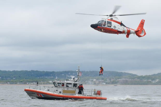 Coast Guard MH-65 Dolphin helicopter hoists a rescue swimmer