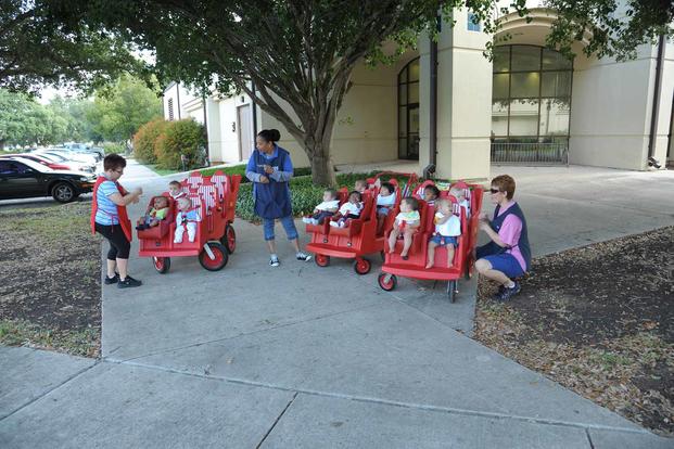 Members from the Child Development Center take children for a stroller ride.