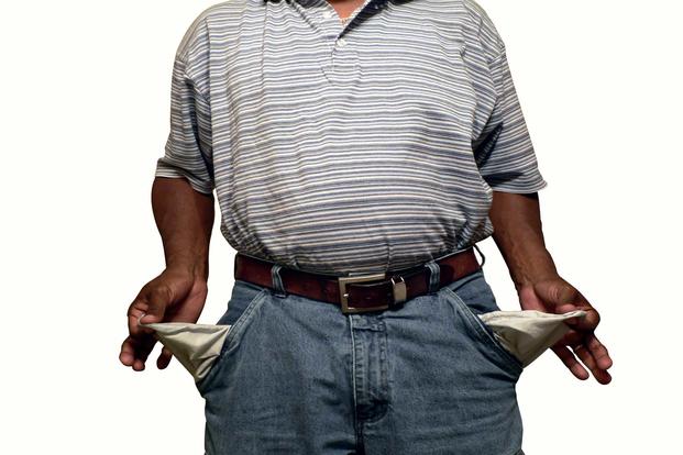 Man with empty pockets turned inside out signifying out of money