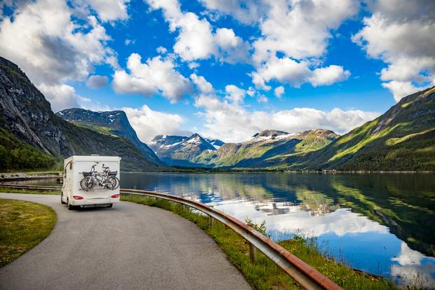 Camper driving alongside pristine mountain lake