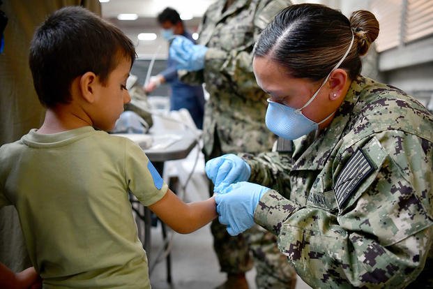 A U.S. Navy Sailor assists an Afghan evacuee.