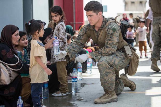 A Marine provides water to a child during evacuation at the airport in Kabul