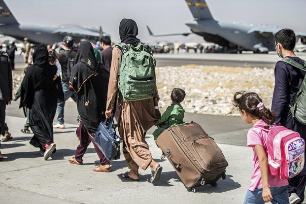 Families walk towards their flight during ongoing evacuations at Hamid Karzai International Airport, in Kabul, Afghanistan.