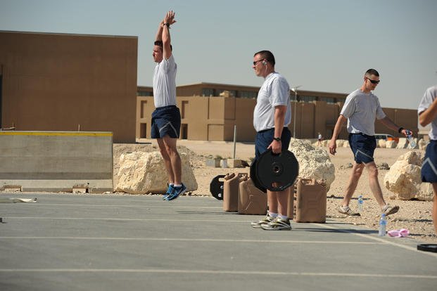 An airman jumps while performing burpees.