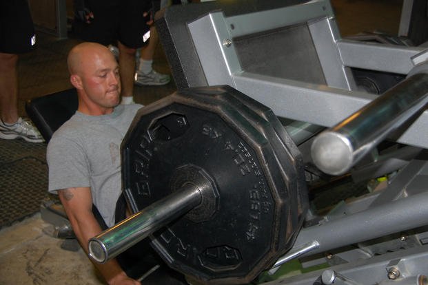 Sergeant competes in leg press during ironman competition.