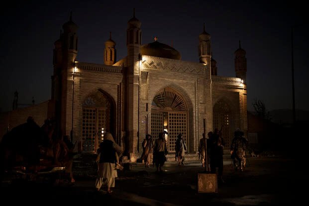 Taliban fighters walk at the entrance of the Eidgah Mosque after an explosion in Kabul