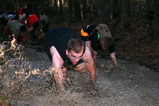 Marines bear-crawl through a mud pit.