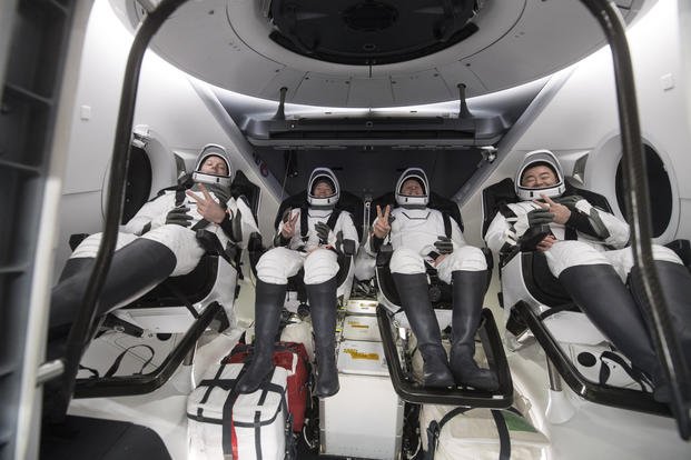 Astronauts gesture inside the SpaceX Dragon spacecraft 