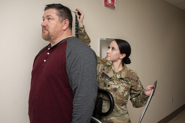 An Army specialist checks a person's height and weight for possible bariatric surgery.