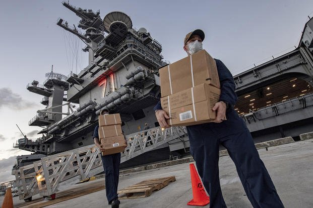 Sailors move MREs for those who have tested negative for COVID-19 to promote social distancing.