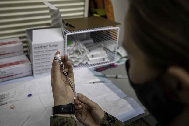 A U.S. Navy Corpsman draws a COVID-19 vaccine from a vial