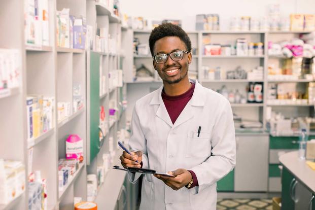 Smiling male pharmacist happily dispensing drugs.