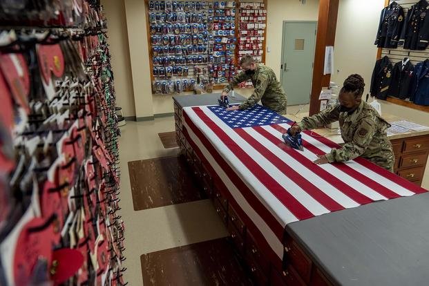 Air Force Staff Sgt. Brandon Barnard, left, and Tech. Sgt. Latasha Major prepare a U.S. flag at Dover Air Force Base, Del.