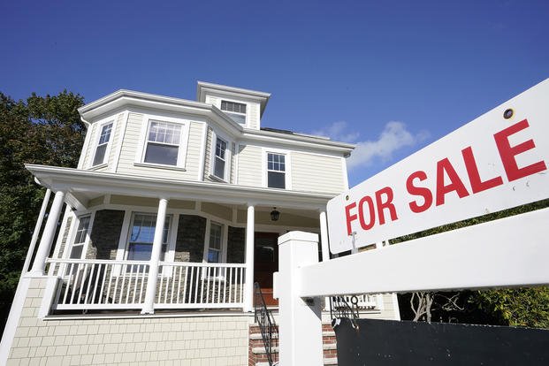 A for-sale sign stands in front of a house in Westwood, Mass.