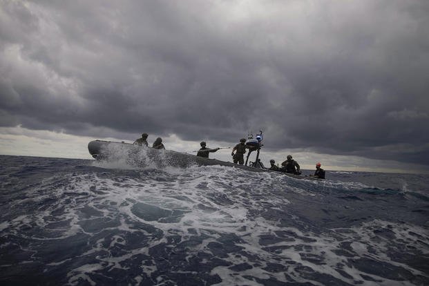 Coast Guardsmen and sailors participate in a noncompliant vessel pursuit tactics exercise in an inflatable boat in the Atlantic Ocean.