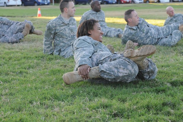 An Army soldier performs a thigh stretch.