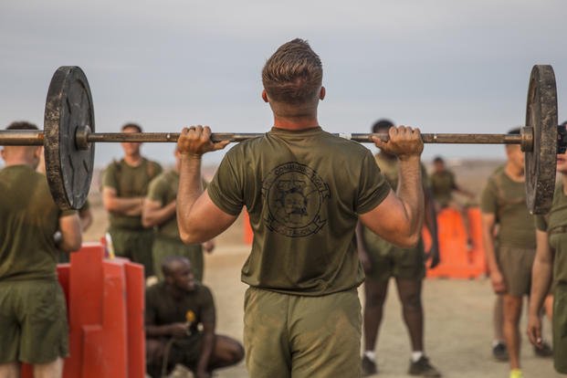 A Marine performs a shoulder press for morning physical training.