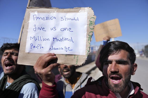 Afghan protesters hold placards and shout slogans.
