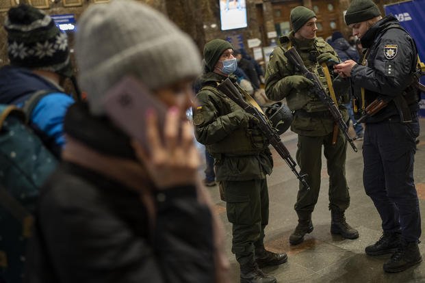 Ukrainian soldiers stand guard at the Kyiv train station.