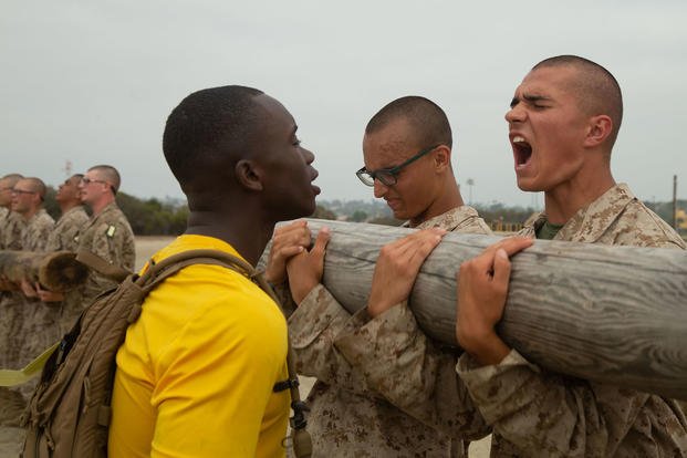 A Marine drill instructor instructs a recruit to yell cadence during a log drill exercise.