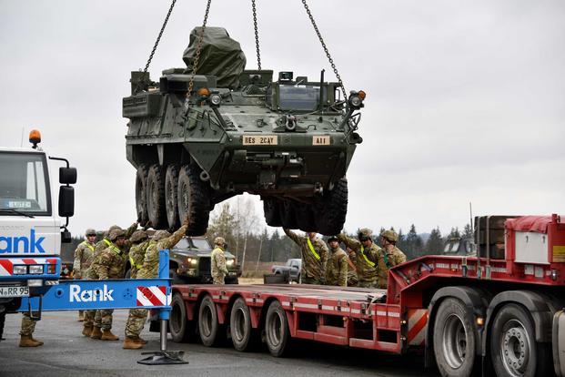 U.S. soldiers load a Stryker armored vehicle onto a truck.