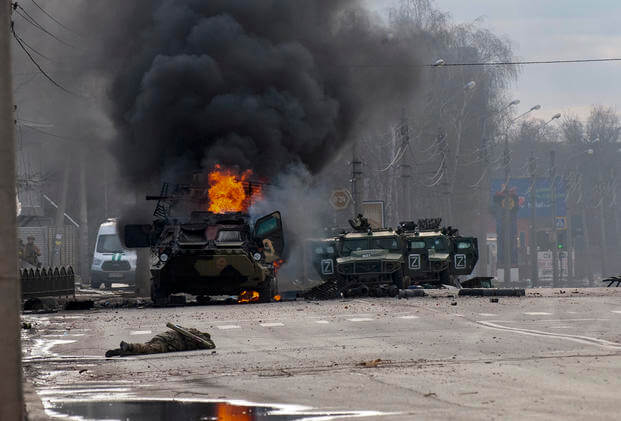 A Russian armored personnel carrier burns amid damaged and abandoned light utility vehicles after fighting in Kharkiv, Ukraine