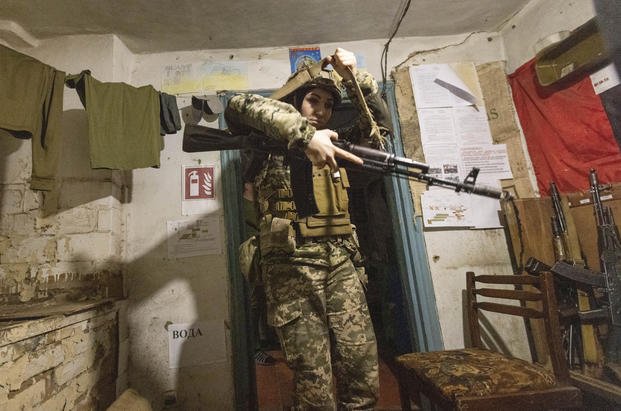 A Ukrainian female soldier takes her gun prior to leaving a shelter.