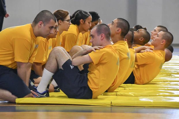 Naval recruits perform the curl-up portion of their initial physical fitness assessment.
