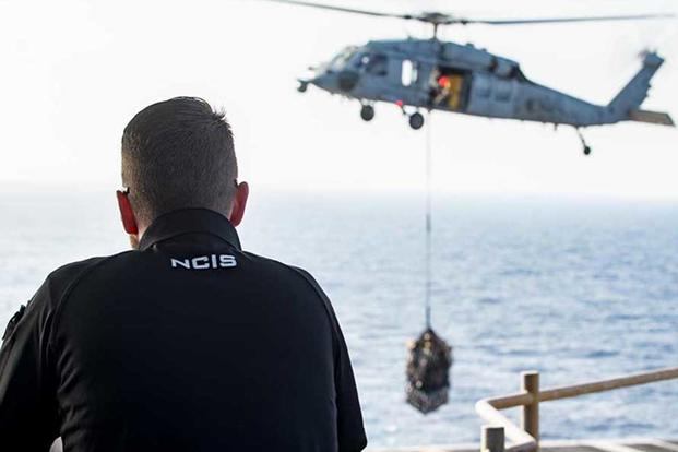 NCIS agent watches a Navy helicopter take off.
