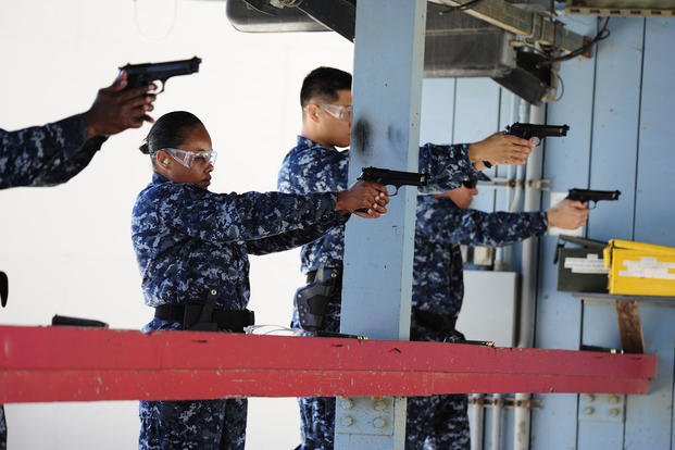 Chief petty officer selectees practice drawing their weapons at a small arms gun range.