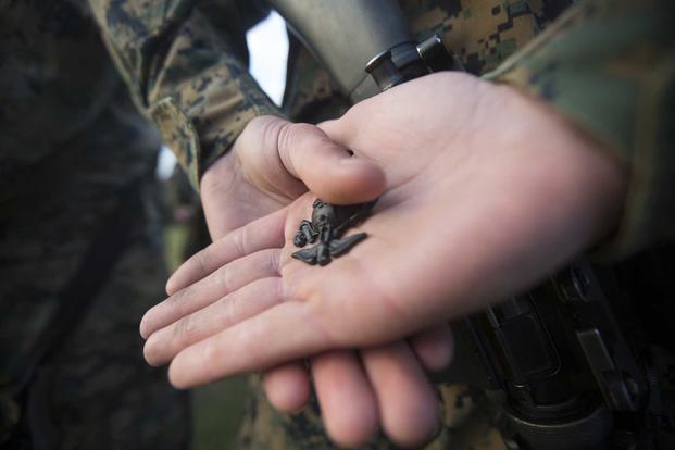 Marine holds Eagle, Globe, and Anchor pin.
