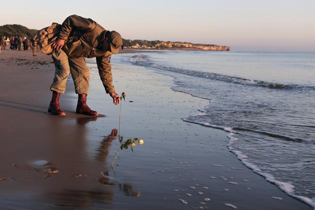 World War II reenactor put roses and flowers at dawn on Omaha Beach, in Saint-Laurent-sur-Mer