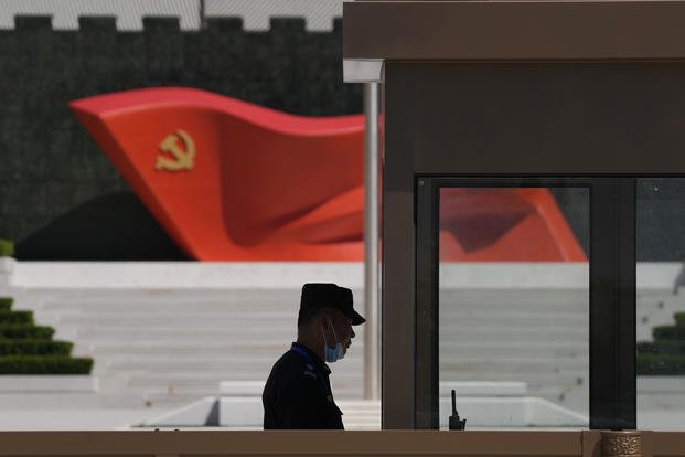 A security guard stands near a sculpture of the Chinese Communist Party flag.