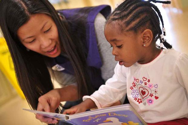 Child Development Center program assistant reads a book to a child.