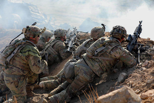 Soldiers with the Oklahoma Army National Guard fire weapons over a trench during a live-fire exercise at Fort Irwin, California.